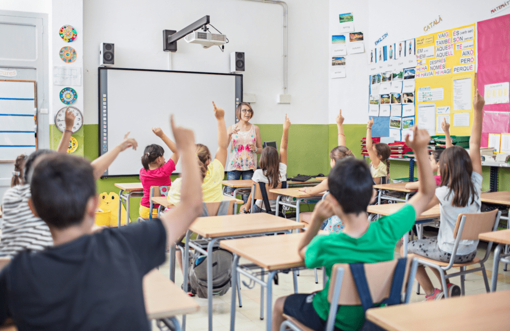 classroom of kids raising hands
